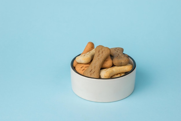 Cookies for dogs in a white bowl on a blue background A delicious treat for dogs with cereals