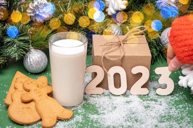 Cookies a glass of milk for Santa on a table covered with snow on the background of Christmas decorations and gifts