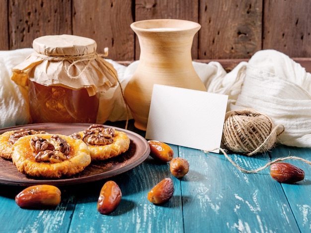 cookies, honey, dates,  milk jug and card on turquoise wood