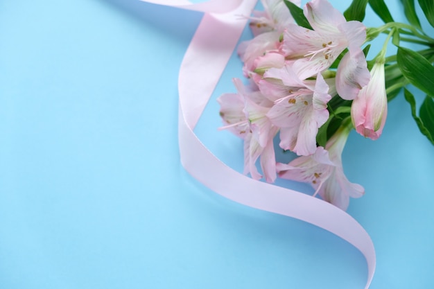 Cookies in the shape of an angel with a pink ribbon with lisianthuses on a blue