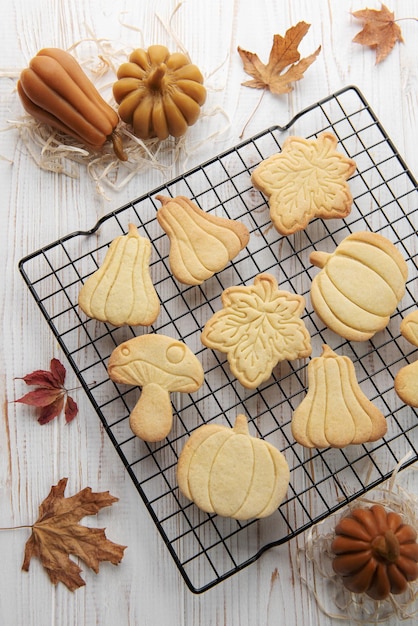 Cookies shaped like pumpkin and leaves on rustic wood background