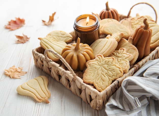 Cookies shaped like pumpkin and leaves on rustic wood background