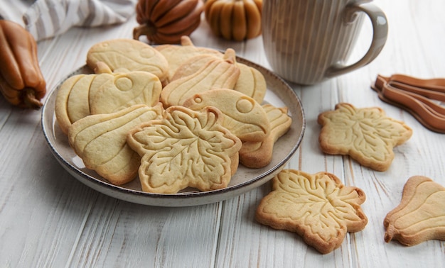 Cookies shaped like pumpkin and leaves on rustic wood background