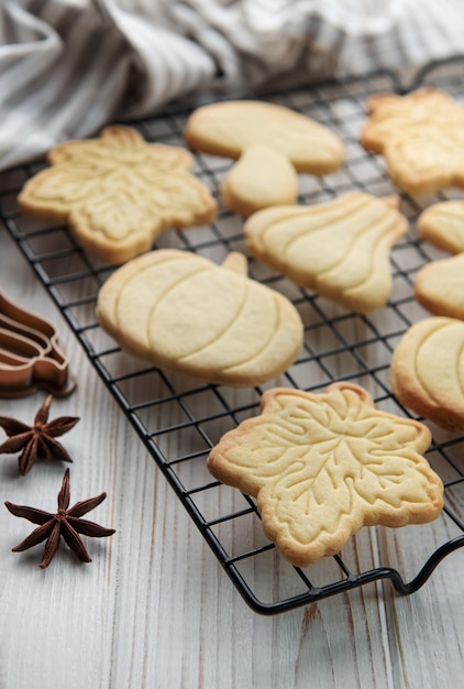 Cookies shaped like pumpkin and leaves on rustic wood background