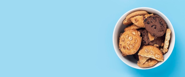 Photo cookies in a white bowl on a blue background. top view, flat lay. banner.