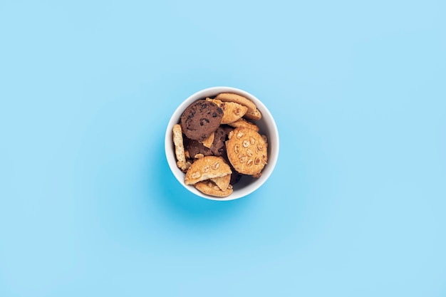 Cookies in a white bowl on a blue background Top view flat lay