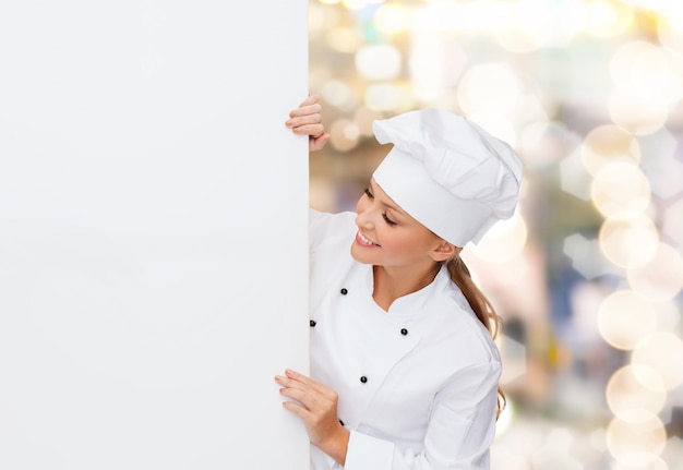 cooking, advertisement and food concept - smiling female chef, cook or baker with white blank board