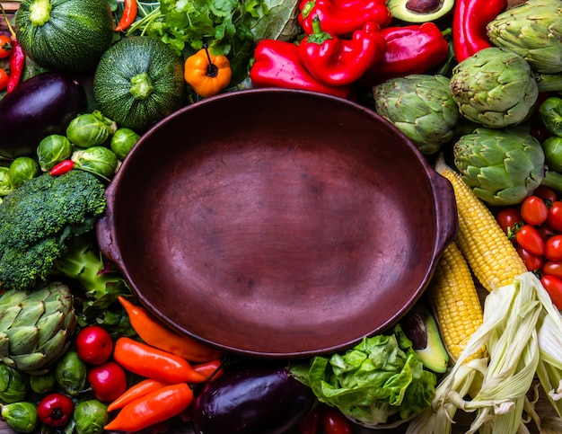 Cooking autumn harvest background concept. Fresh organic vegetables around empty clay pot