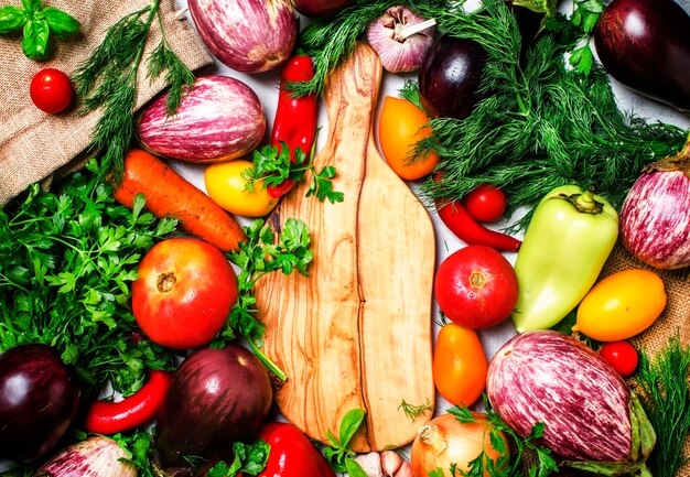 Cooking background fresh vegetables and spicy herbs on a cutting board top view