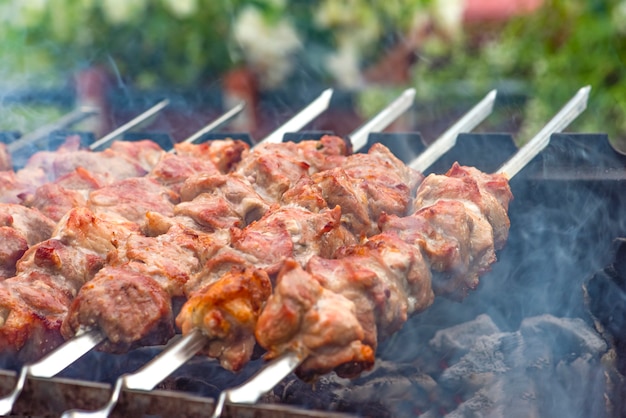 Cooking barbecue, grilled meat barbecue. Cooking pork shashlik on metal skewers. Smoke from embers builds up over the dish. Advertising banner with copy space