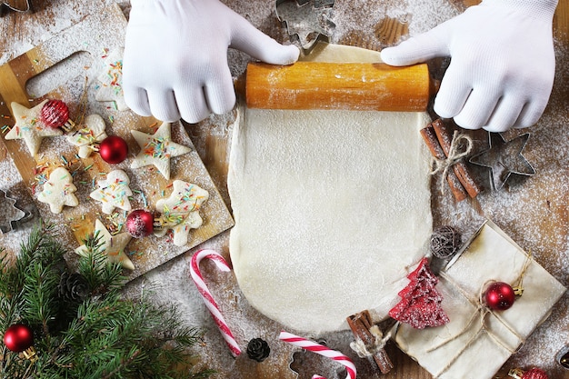 Cooking butter biscuits of different shapes on a wooden table with Christmas accessories