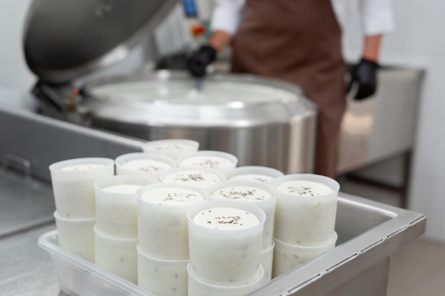 Cooking cheese from a private cheese factory Man checks consistency of raw materials with a spoon