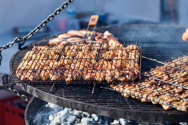 Cooking chicken barbecue on BBQ grill basket with wooden handle thick delicious smoke