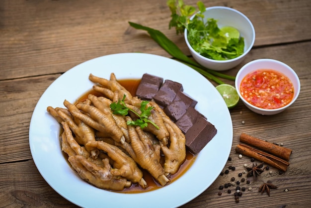 Cooking chicken feet foot stew on white with herbs and spices ingredients with chilli lemon vegetable on wooden background Asian chinese food menu stew Thai food chicken feet soup stewed