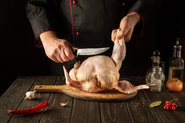 Cooking chicken in the restaurant kitchen The chef cuts raw chicken with a knife