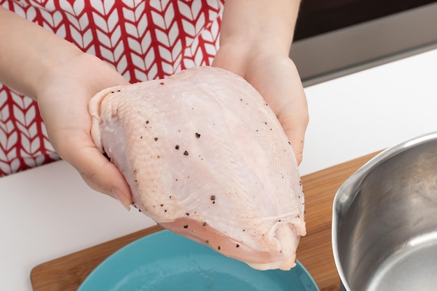 Cooking a delicious diet dinner Female hands put raw chicken breast in a pan