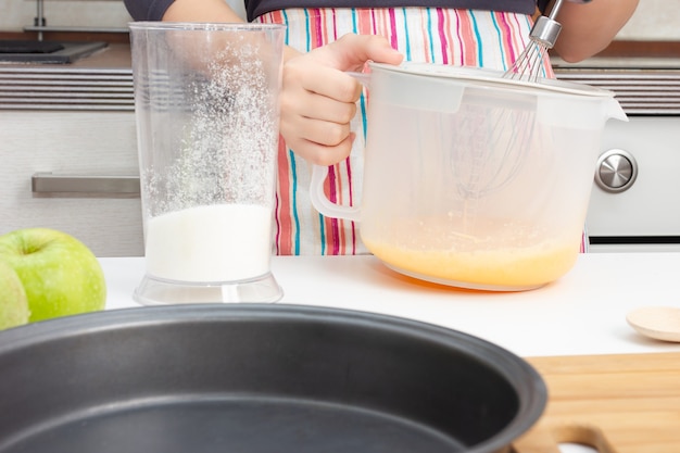 Cooking dough. Girl beats with a mixer chicken eggs with sugar in a bowl in the kitchen.