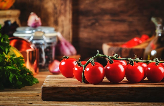 Cooking food background with tomatoes pumpkins herbs on rustic wooden kitchen table with cast iron pan spice grinders cutting board spices and seasonings storage jars