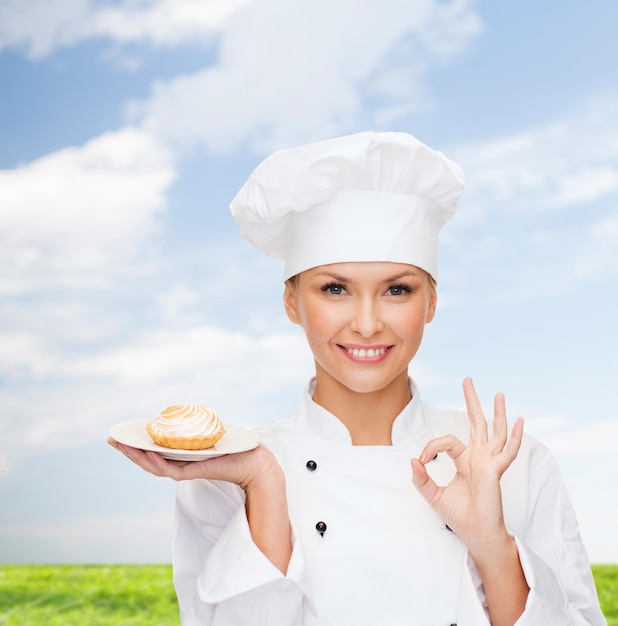 cooking and food concept - smiling female chef, cook or baker with pie on plate and ok sign