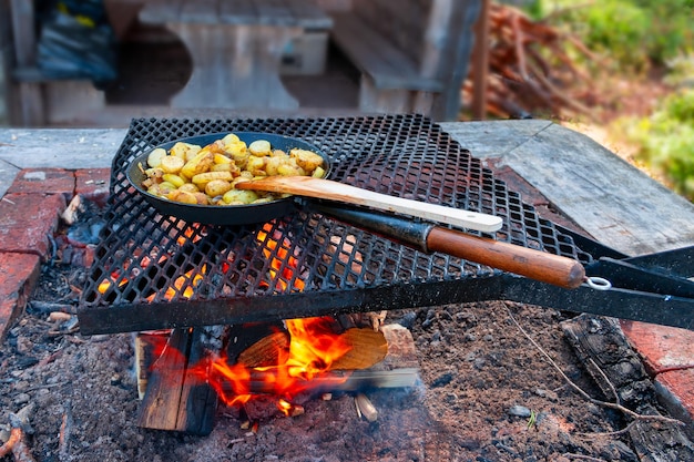 Cooking fried potatoes in a frying pan over a campfire in the Swedish wilderness