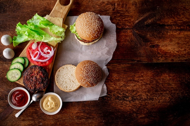 Cooking hamburger or cheeseburger Different ingredients for a classic hamburger Place for text Wooden background Hamburger day