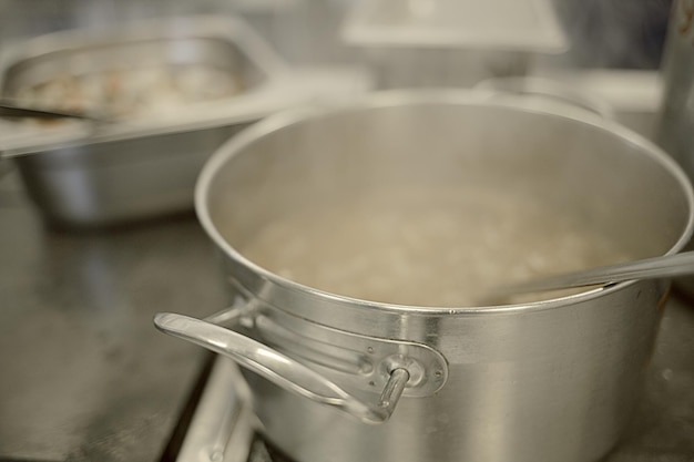 Cooking in the kitchen An aluminum pot is steaming on an electric stove