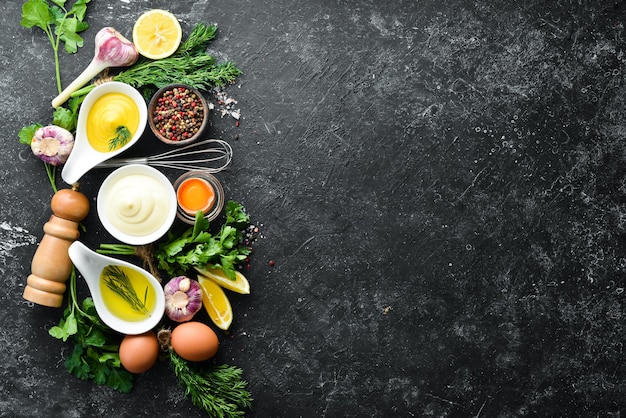 Cooking mayonnaise sauce Oil mustard and eggs Culinary black stone background Top view