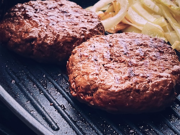 Cooking minced beef burger on cast iron grill skillet outdoors red meat on frying pan grilling food in the garden English countryside living