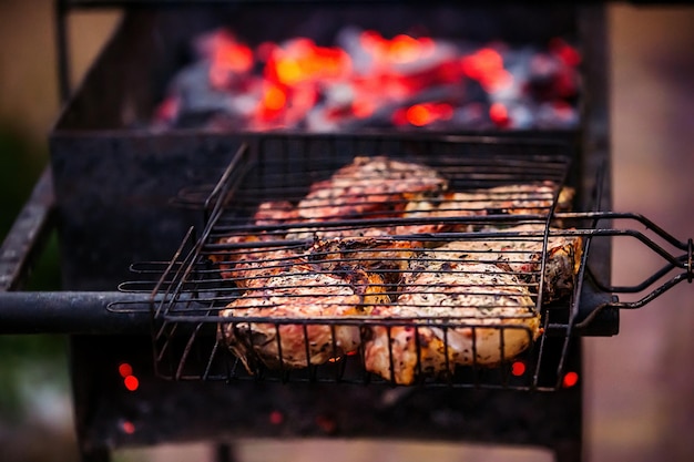 cooking in nature in the grill burning coals on which large pieces of meat are fried on a grid