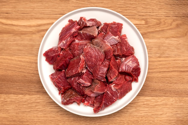 Cooking pilaf in a cauldron, a recipe for real pilaf. Ingredients for cooking pilaf on a wooden background. Raw meat on a wooden cutting board, cut into pieces.