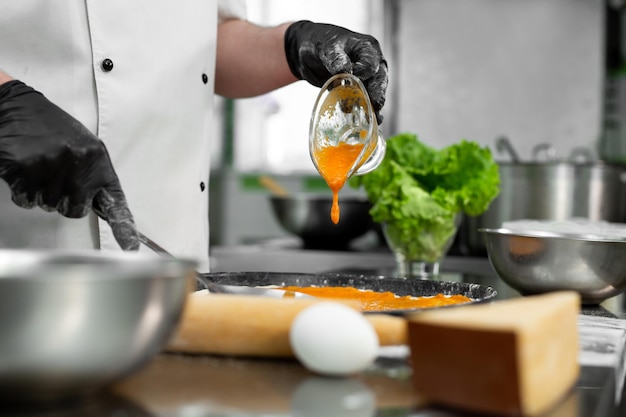 Cooking pizza. Close-up of the chef's hand pouring sauce over the pizza dough.