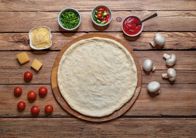 Cooking pizza. Rolling out the raw dough on a wooden board.