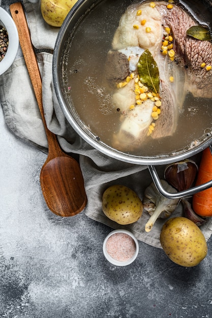 Cooking pot with  bone broth meat. Vegetables cooking ingredients and spices on kitchen table.  Top view