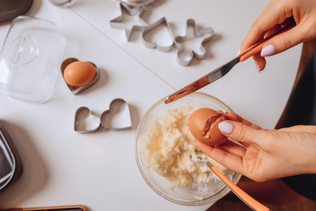 cooking process Womens hands break an egg with knife Add the ingredients for dough to the bowl