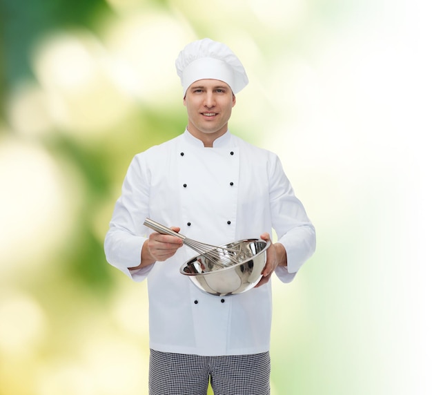 cooking, profession and people concept - happy male chef cook holding bowl and whipping something with whisk over green background