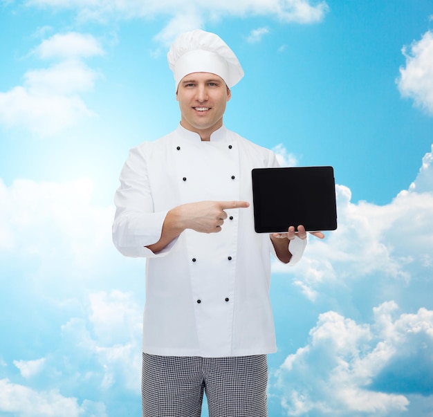 cooking, profession and people concept - happy male chef cook showing tablet pc computer black blank screen over blue sky with clouds background