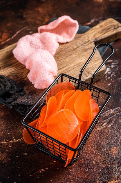 Cooking raw kerupuk or prawn shrimp crackers chips Asian fastfood Dark background Top view