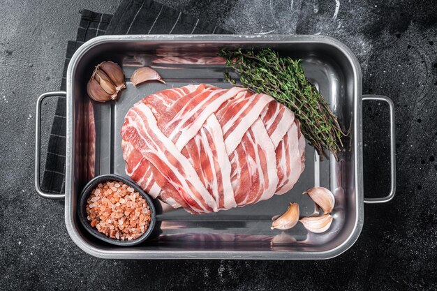 Cooking raw meatloaf with ground beef meat and bacon in steel tray fresh meat loaf Black background Top view