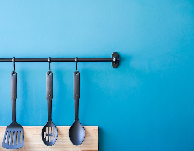 Cooking utensil hanging on the kitchen wall, blue minimal spoon household background with 