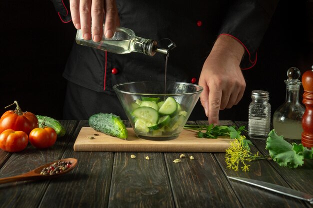 Cooking vegetable salad by the hands of the chef for breakfast Adding Olive Oil to Cucumber and Tomato Salad