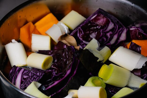 Cooking vegetables in a saucepan homemade winter soup with red cabbage leek and butternut pieces