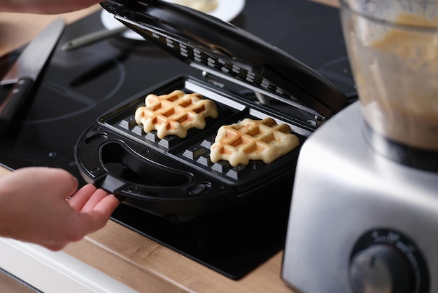 Cooking waffles in waffle iron at home closeup