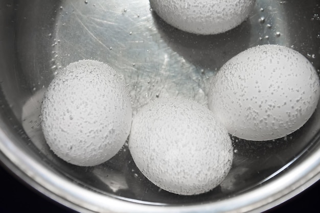 Cooking white chicken eggs in a saucepan.