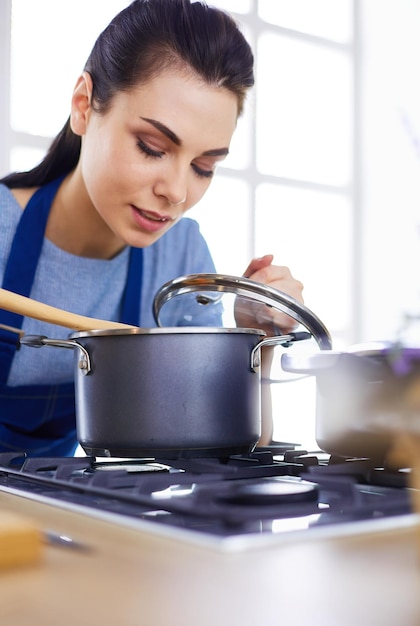 Cooking woman in kitchen with wooden spoon