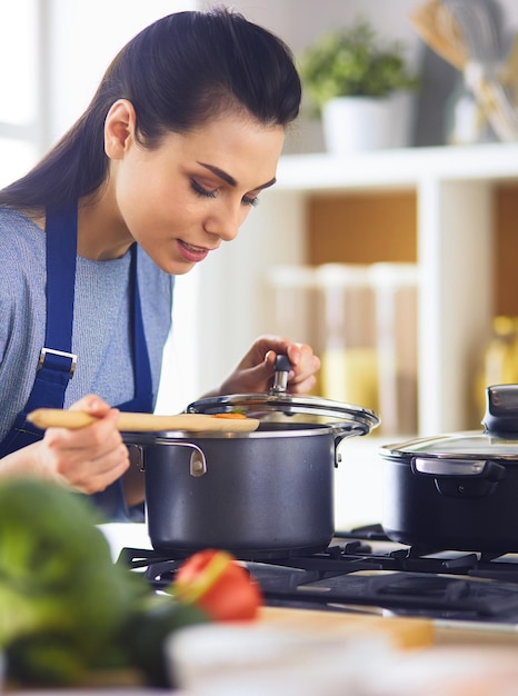 Cooking woman in kitchen with wooden spoon