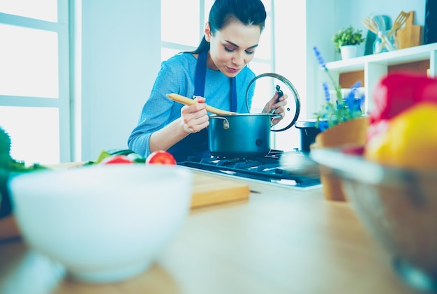 Cooking woman in kitchen with wooden spoon