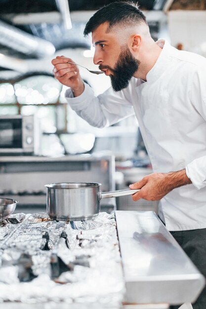 Cooks delicious soup Chef in white uniform cooking food at kitchen Busy day at work