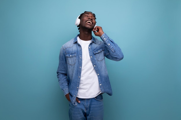 Cool american man with dreadlocks in denim jacket dancing to music with headphones