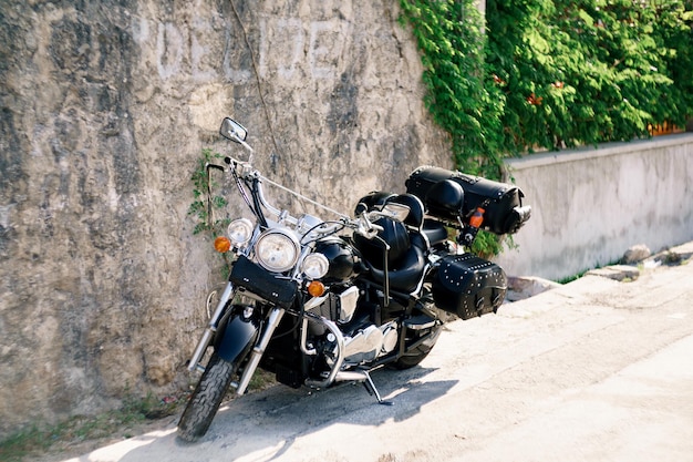 Cool black biker chopper stands near a stone wall in the street