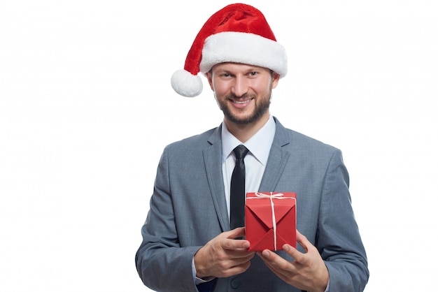 Cool businessman. Portrait of handsome man wearing Christmas hat posing with small gift in hands.